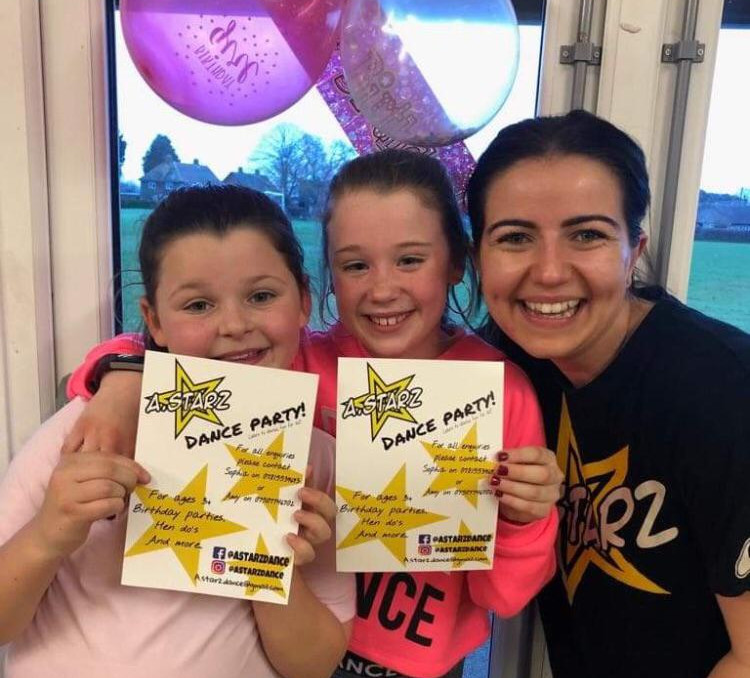 Dance teacher and two girls smiling and holding dance party certificates